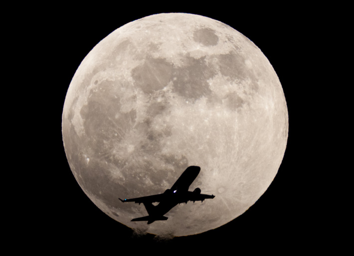 満月を横切る航空機